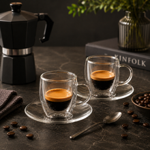 Lade das Bild in den Galerie-Viewer, Zwei doppelwandige Espressogläser Triest mit Espresso neben schwarzer Mokkakanne auf dunkler Steinplatte