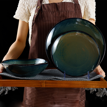 Lade das Bild in den Galerie-Viewer, Keramik Tellerset „Gothenburg“ in Grün-Blau, Person serviert Speisen auf mediterranen Tellern