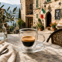 Lade das Bild in den Galerie-Viewer, Doppelwandiges Espressoglas Triest mit Espresso auf einem Café-Tisch vor einer italienischen Altstadtgasse
