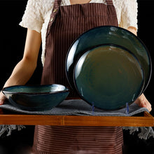 Lade das Bild in den Galerie-Viewer, Person präsentiert Kadum Frühstücksteller 21 cm und Schüsseln – handbemalt in Blau-Grün-Gold
