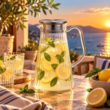 Lade das Bild in den Galerie-Viewer, OONYQ Striped Karaffe 1500 ml – bruchsichere Karaffe aus Tritan mit Rillenoptik und Edelstahldeckel mit Zitronenlimonade auf der Terrasse
